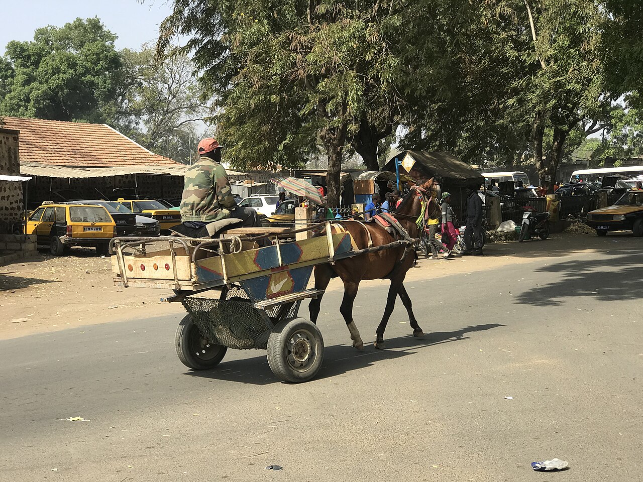 Charrette tirée par un cheval dans une rue de Thiès, utilisée pour transporter du ciment.